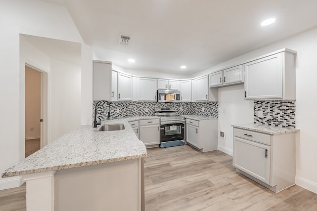 kitchen featuring backsplash, sink, light stone countertops, light wood-type flooring, and appliances with stainless steel finishes