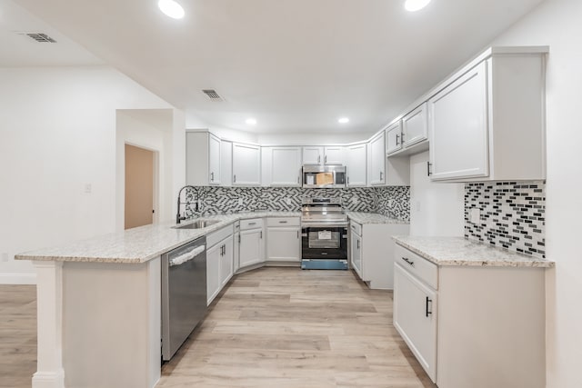 kitchen featuring light hardwood / wood-style floors, white cabinetry, kitchen peninsula, and stainless steel appliances