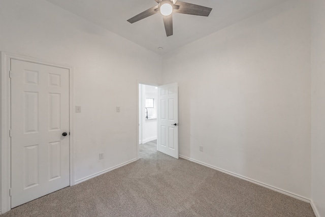 carpeted spare room with ceiling fan and vaulted ceiling