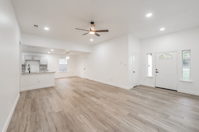 unfurnished living room featuring ceiling fan, light hardwood / wood-style flooring, and sink