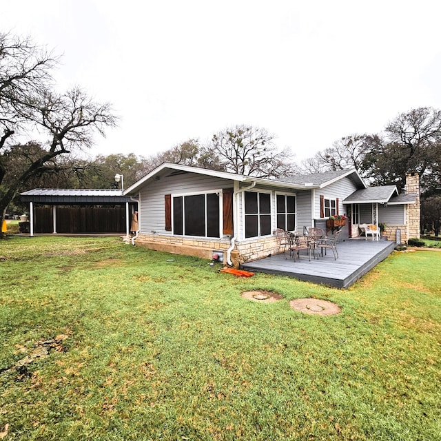 rear view of property with a carport, a wooden deck, and a lawn