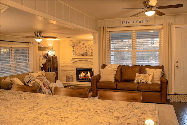 living room with hardwood / wood-style floors, crown molding, a fireplace, and ceiling fan