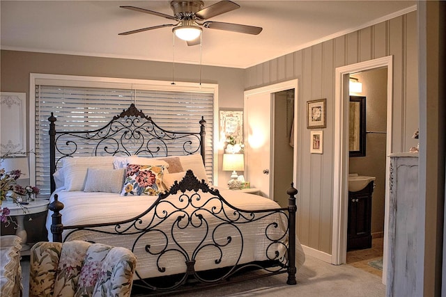 carpeted bedroom featuring crown molding, ensuite bathroom, and ceiling fan