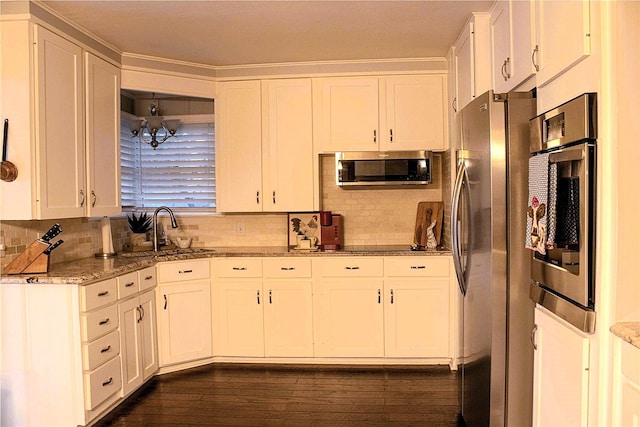 kitchen featuring stainless steel appliances, white cabinetry, decorative backsplash, and dark stone counters