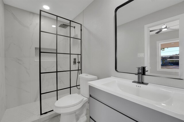 bathroom with ceiling fan, toilet, vanity, and tiled shower