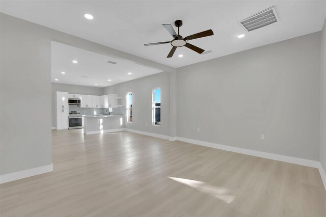 unfurnished living room with ceiling fan, light wood-type flooring, and sink