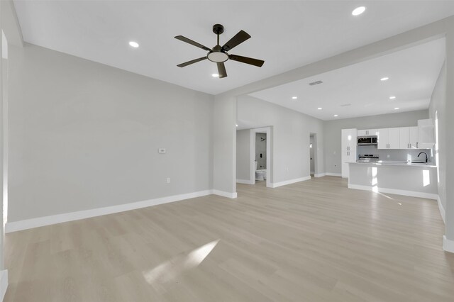 unfurnished living room featuring ceiling fan, light hardwood / wood-style floors, and sink