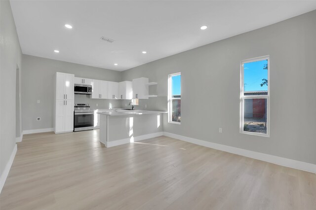 kitchen with sink, kitchen peninsula, light hardwood / wood-style flooring, appliances with stainless steel finishes, and white cabinetry