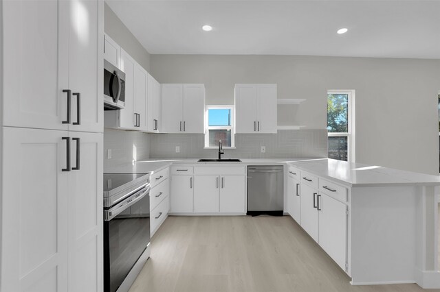 kitchen featuring decorative backsplash, appliances with stainless steel finishes, light wood-type flooring, sink, and white cabinets