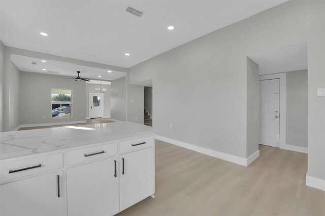 kitchen with ceiling fan, white cabinets, light stone countertops, and light wood-type flooring