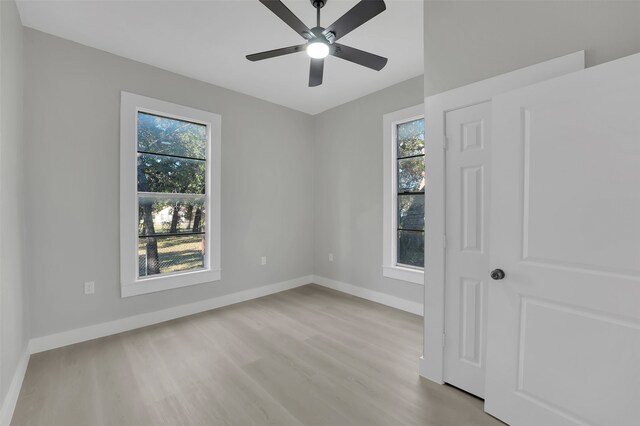 spare room with ceiling fan, a healthy amount of sunlight, and light wood-type flooring