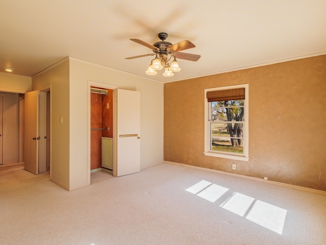 unfurnished bedroom with ceiling fan, light colored carpet, ornamental molding, and a closet