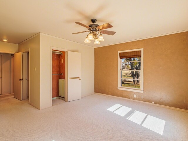 unfurnished bedroom with ceiling fan, light colored carpet, ornamental molding, and a closet