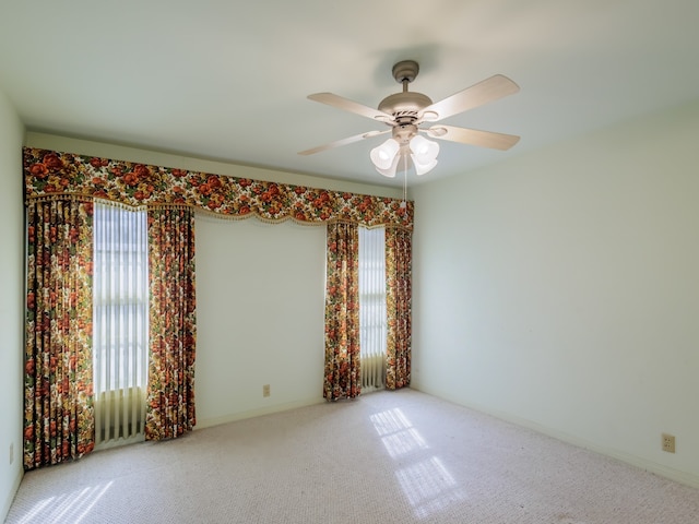 empty room featuring carpet flooring, ceiling fan, and a wealth of natural light