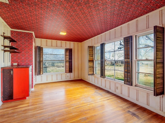 unfurnished dining area with wooden walls, light hardwood / wood-style flooring, and lofted ceiling