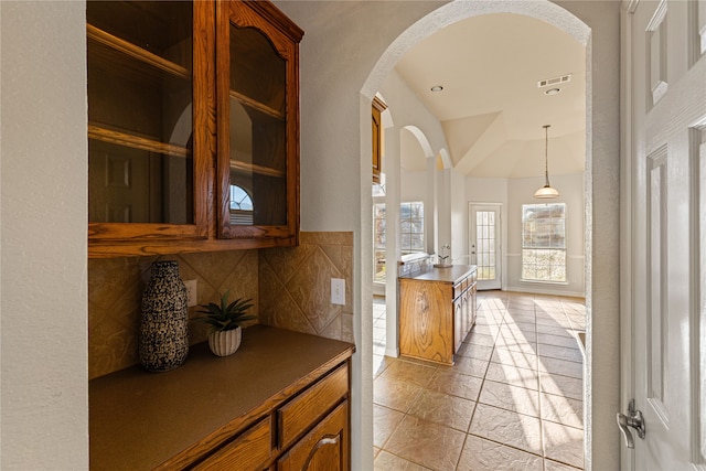 interior space featuring decorative backsplash, light tile patterned floors, and hanging light fixtures