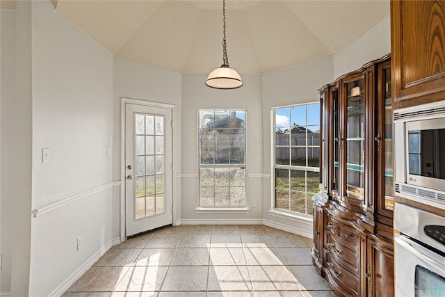 interior space with a wealth of natural light, light tile patterned floors, and vaulted ceiling