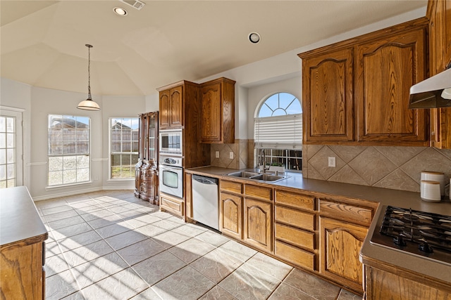 kitchen with decorative backsplash, appliances with stainless steel finishes, sink, decorative light fixtures, and lofted ceiling