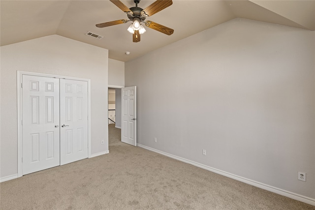 unfurnished bedroom with ceiling fan, a closet, light carpet, and vaulted ceiling