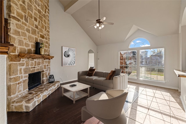 living room with ceiling fan, a fireplace, high vaulted ceiling, and light hardwood / wood-style flooring