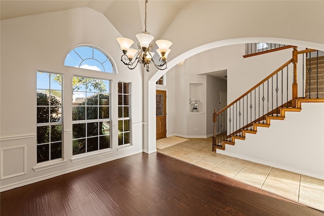 entrance foyer featuring high vaulted ceiling, a notable chandelier, and hardwood / wood-style flooring