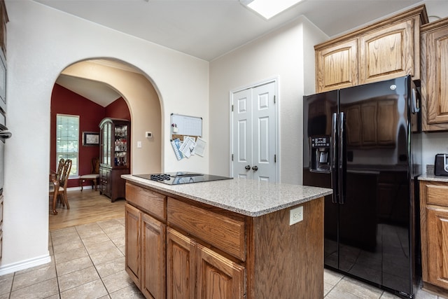 kitchen with light tile patterned floors, a kitchen island, and black appliances