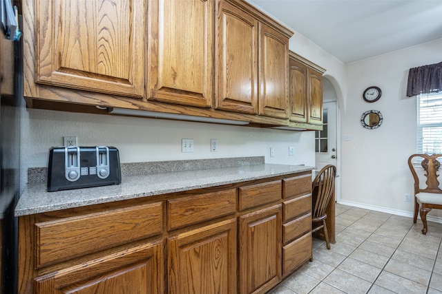 kitchen with light tile patterned floors and light stone counters