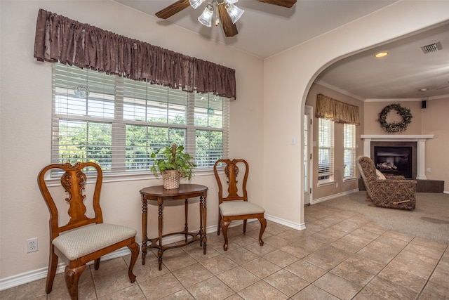 living area featuring a tiled fireplace, crown molding, ceiling fan, and light tile patterned floors