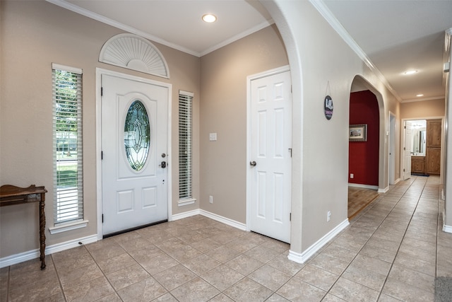 entrance foyer featuring light tile patterned floors and crown molding