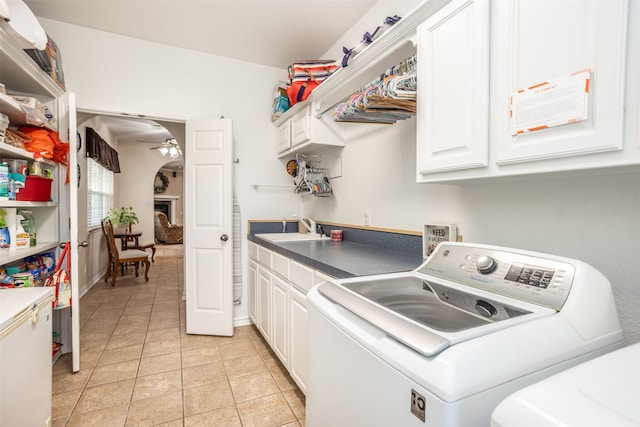 clothes washing area featuring ceiling fan, sink, cabinets, washing machine and dryer, and light tile patterned floors