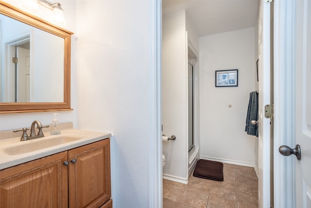 bathroom with tile patterned flooring, vanity, a shower with shower door, and toilet