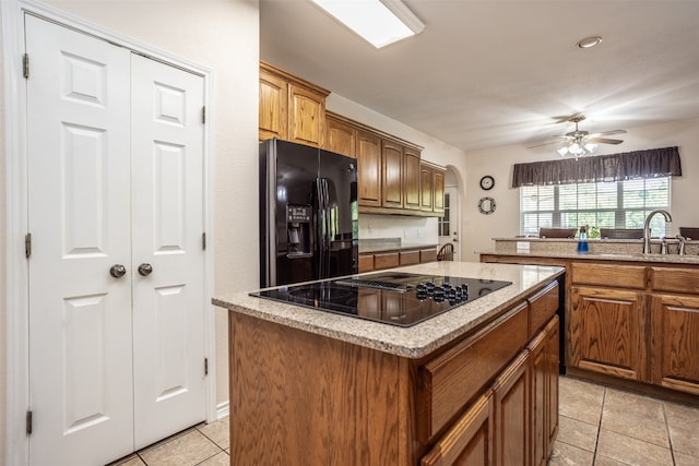 kitchen featuring black appliances, sink, ceiling fan, light tile patterned floors, and a kitchen island