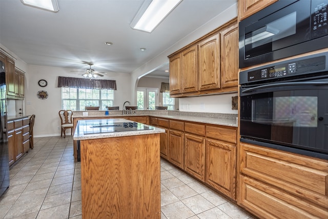 kitchen with kitchen peninsula, a center island, light tile patterned floors, and black appliances