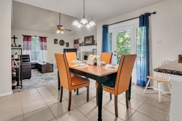 dining space featuring vaulted ceiling, light tile patterned flooring, and ceiling fan with notable chandelier