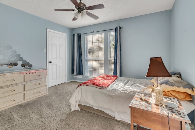 bedroom with ceiling fan, light colored carpet, and a textured ceiling