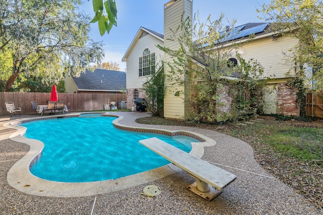 view of swimming pool featuring a patio area and a diving board