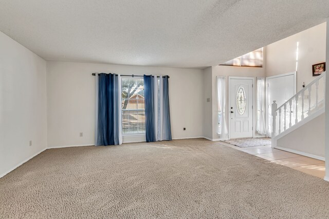 unfurnished dining area featuring light colored carpet, a textured ceiling, and a notable chandelier