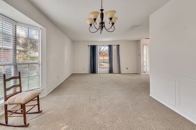 unfurnished dining area featuring light carpet, a notable chandelier, and a textured ceiling