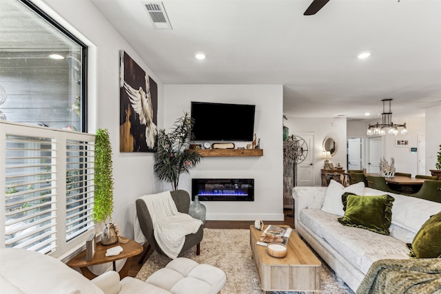 living room with ceiling fan with notable chandelier and light hardwood / wood-style floors