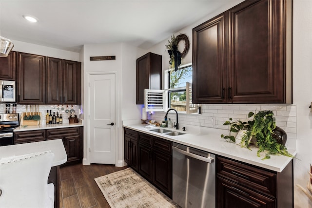 kitchen featuring appliances with stainless steel finishes, dark hardwood / wood-style flooring, backsplash, dark brown cabinetry, and sink