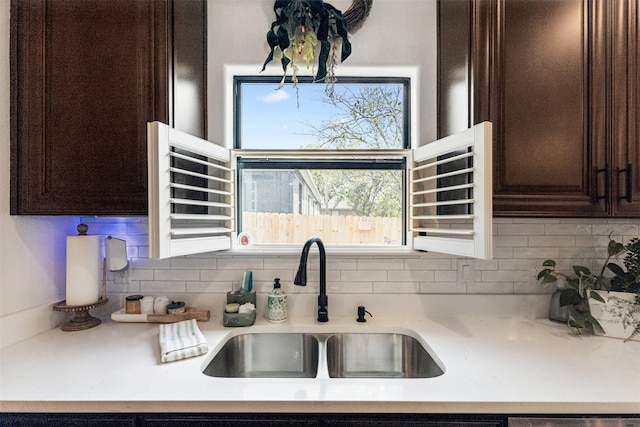 kitchen featuring dark brown cabinets, sink, and tasteful backsplash