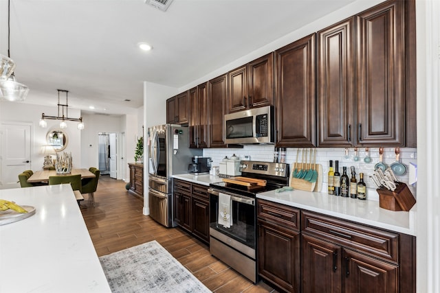 kitchen featuring tasteful backsplash, wood-type flooring, pendant lighting, and appliances with stainless steel finishes