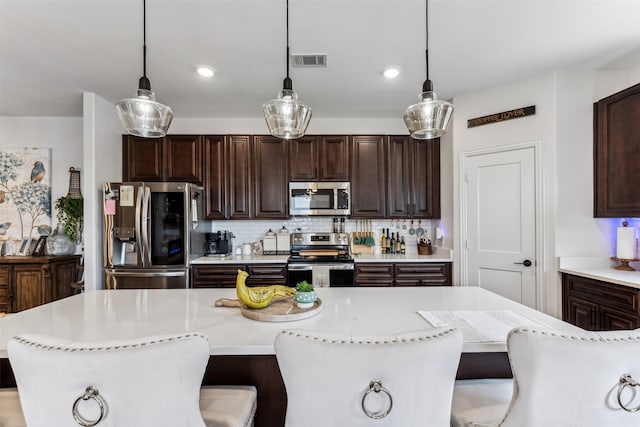 kitchen featuring pendant lighting, dark brown cabinets, stainless steel appliances, and a breakfast bar area