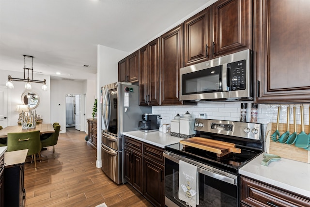 kitchen featuring stainless steel appliances, backsplash, light hardwood / wood-style floors, decorative light fixtures, and dark brown cabinets