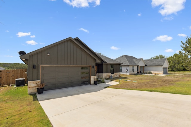 view of front of home featuring cooling unit, a front yard, and a garage