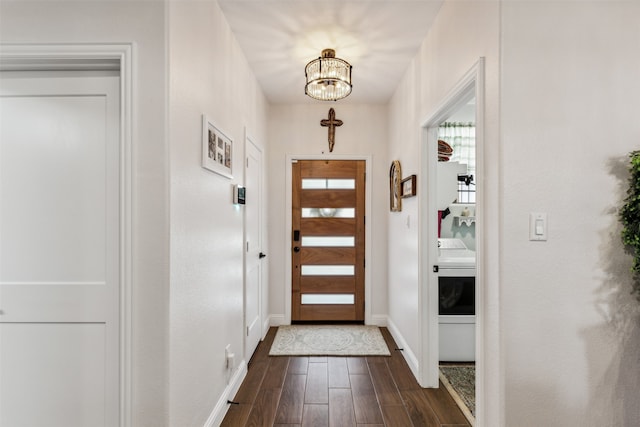 doorway with washer / dryer, dark hardwood / wood-style flooring, and a notable chandelier