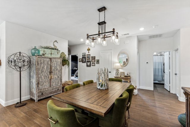 dining area with dark wood-type flooring and an inviting chandelier