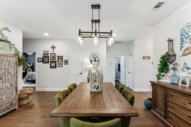 dining space with dark hardwood / wood-style flooring and an inviting chandelier