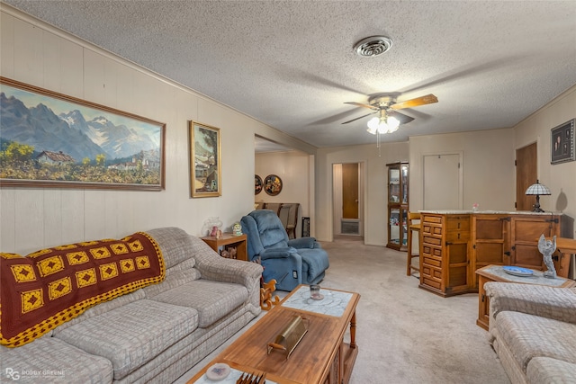 carpeted living room with ceiling fan, wood walls, and a textured ceiling