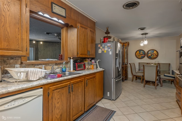 kitchen with stainless steel refrigerator with ice dispenser, tasteful backsplash, white dishwasher, sink, and light tile patterned floors